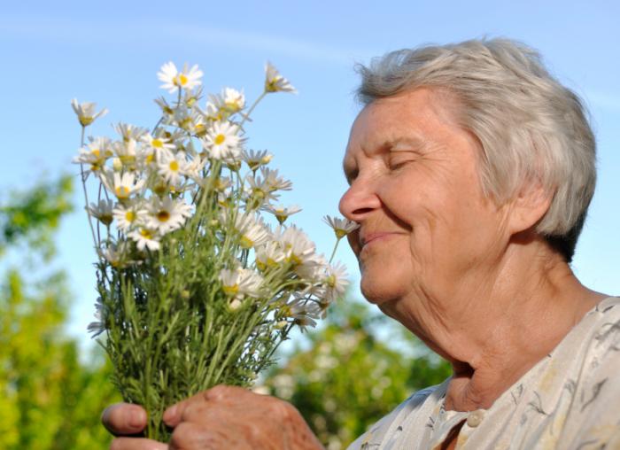 Older lady smelling flowers