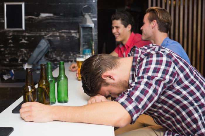 Drunk young man slumped at bar.